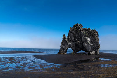 Rock formation at beach against sky