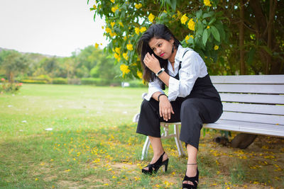Full length of fashionable young woman sitting on bench