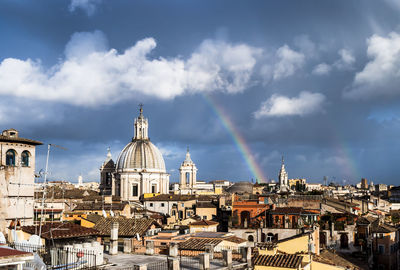 Rainbow over city against sky