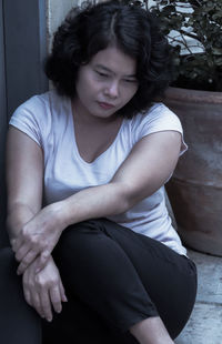 Mid adult woman sitting against wall