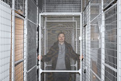 Portrait of man standing by fence in underground