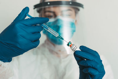 Close-up of doctor injecting syringe in vial at hospital