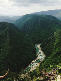 Cloudy mountain behind the green mountains with river and tree field