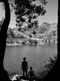 Father and son standing on tree by lake