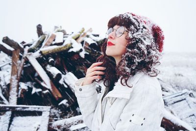 Woman standing on snow by wood