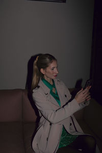 Portrait of young woman sitting on sofa at home