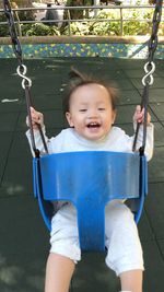 Smiling baby girl sitting on swing in playground