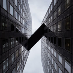 Directly below shot of elevated walkway amidst office buildings against sky