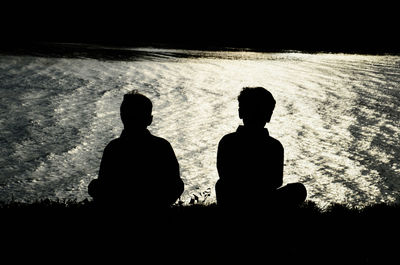 Silhouette friends standing on beach against sky during sunset
