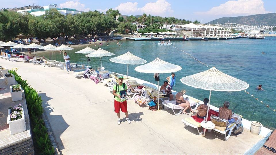 water, large group of people, vacations, beach, person, lounge chair, sea, parasol, beach umbrella, chair, sunshade, in a row, sunlight, relaxation, high angle view, leisure activity, lifestyles, day, mixed age range