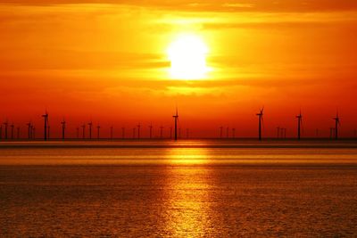 Scenic view of sunrise over silhouette of wind turbine farms 