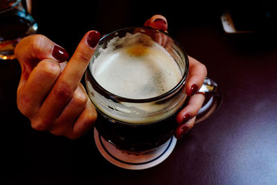 Cropped hand gesturing obscene gesture while having beer on table