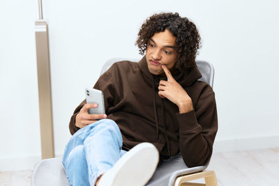 Young woman using mobile phone while sitting on table