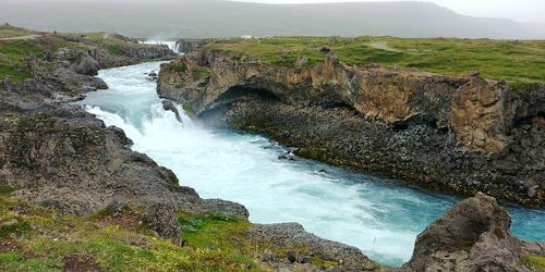 Scenic view of waterfall against sky