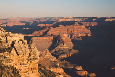 Scenic view of eroded landscape against clear sky during sunset