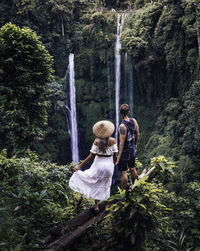 Rear view of woman on waterfall in forest
