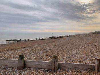 Empty benches on beach against sky