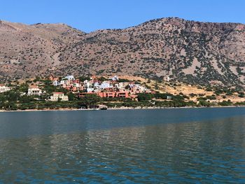 Town by lake and mountains against clear sky