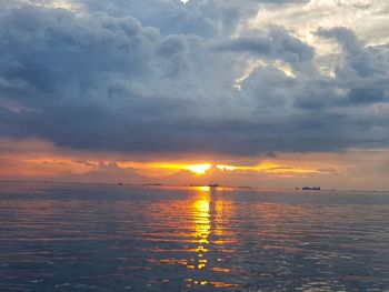 Scenic view of sea against dramatic sky during sunset