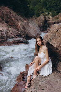 Portrait of young woman sitting on rock