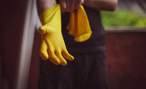 Caucasian male builder wears yellow gloves.