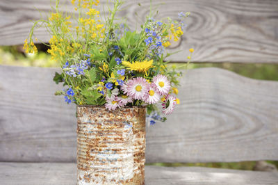 A bouquet of wildflowers of forget-me-nots, daisies and yellow dandelions in full bloom in a rusty