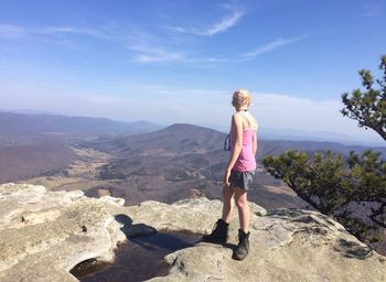 Full length of hiker standing on mountain against sky during sunny day