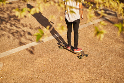 Low section of woman walking on street during sunny day