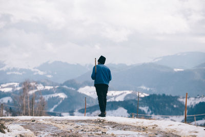 Rear view of man standing on snow covered mountain