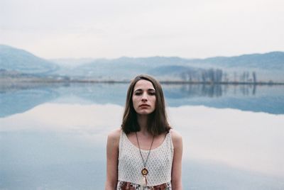 Portrait of beautiful young woman in lake against sky