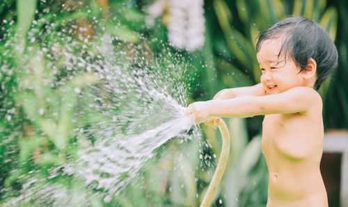 Full length of shirtless boy splashing water