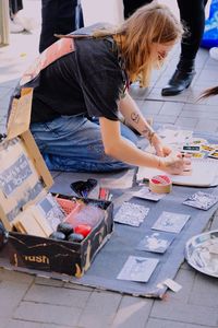 High angle view of girl drawing in paper on footpath