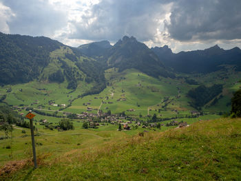 Scenic view of green landscape and mountains against sky