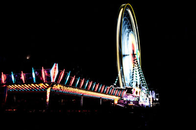 Illuminated ferris wheel against sky at night