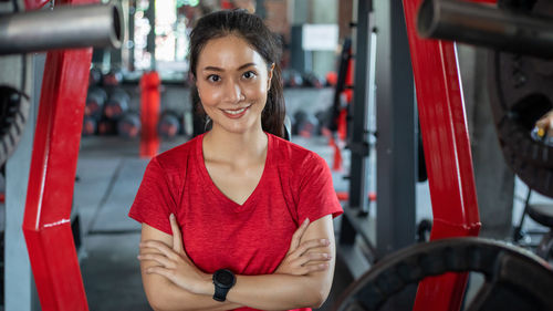 Portrait of smiling young woman with arms crossed in gym