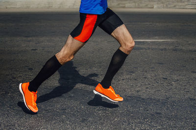 Legs athlete in compression socks run marathon on asphalt