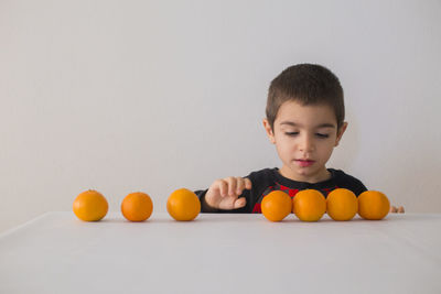 Full length of boy with orange against white background