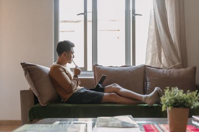 Young woman using laptop while sitting on sofa at home