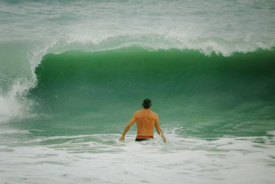 Rear view of shirtless man standing in sea