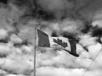 Low angle view of canadian flag against cloudy sky