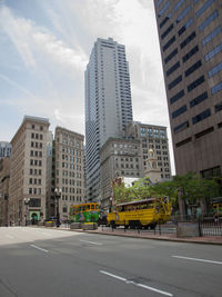 Road by buildings against sky in city