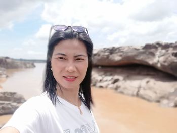 Portrait of smiling woman on beach against sky