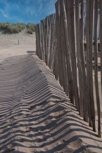 Wooden posts on sand at beach against sky