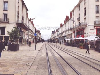 People on railroad tracks amidst buildings in city