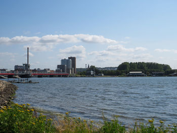 Scenic view of river by buildings against sky