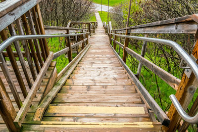 Large wooden staircase with hand rail leading down to a roadway in a park