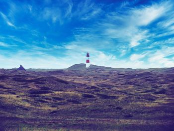 Lighthouse on road amidst buildings against sky