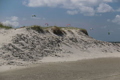 Kites flying over hill against sky