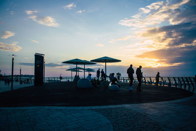 Silhouette people on beach against sky during sunset