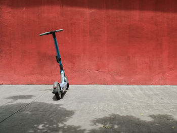 Low section of an electric scooter parked infront of a red wall in the city